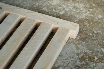 The process of making joints wood lath in the carpentry workshop. Raw pinewood and sawdust on the concrete floor.