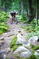 Fototapeta na wymiar Young caucasian cyclist repairs a mountain bike in the mountains in the forest.