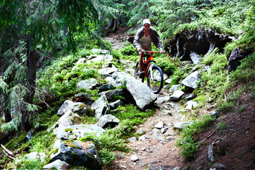 Young caucasian cyclist on a mountain bike rides along mountain trails in a mountain forest.