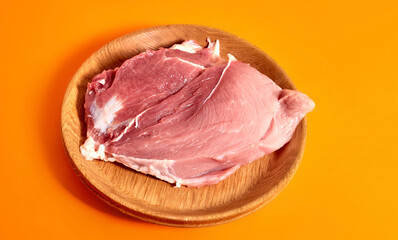 A plate of raw pork meat on an orange background