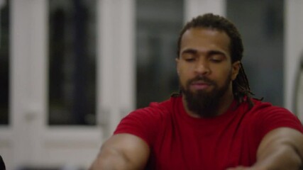 Strong attractive black male using a rowing machine inside the gym