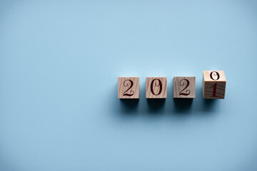 Top view. Wooden cube with word 2020 2021 New Year concept on blue background. Closeup and copy space on left for design or text.