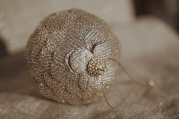 Close-up of beautiful beige Christmas ball on a beige glittering background. Selective focus , blurred photo. 