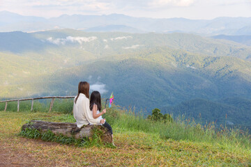 Fototapeta na wymiar Mother and daughter sit and watch the beautiful mountain view Look at the vast nature