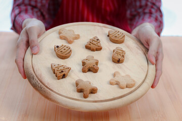 Homemade ginger bread cookies, closeup of hand holding Christmas gingerbread cookies on tray after baking, making Xmas gingerbread cookie, preparing bakery, process of baking and cooking at home