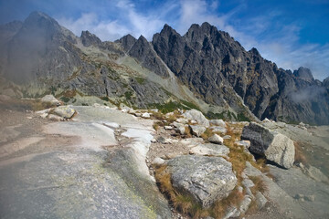 Fototapeta na wymiar Velka Studena dolina, High Tatras - stones by the tourist trail with the background of Tatra peaks during the hike to Zbojnicka chata.