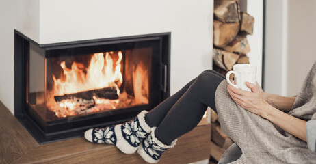 Woman relaxing near the fireplace, holding cup of tea, enjoying life at home. Winter fun, lifestyle, leisure, lockdown, holidays, vacations, Christmas, New Year concept