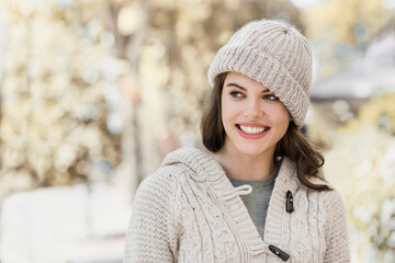 Beautiful young woman winter portrait. Smiling happy girl wearing warm clothes and hat in a city in autumn.
