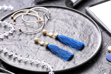 Plate with blue earrings and bracelets on dark background
