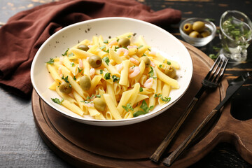 Plate of tasty pasta with shrimps and olives on wooden table