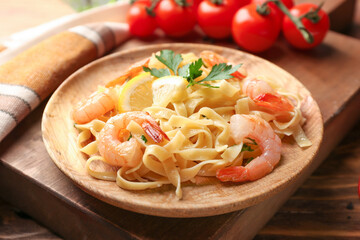 Plate of tasty pasta with shrimps on wooden table