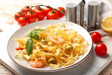 Plate of tasty pasta with shrimps and olives on table