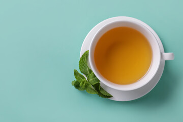 Cup of tasty mint tea on color background