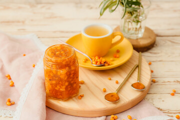 Tasty homemade sea buckthorn jam and cup of tea on table