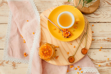 Tasty homemade sea buckthorn jam and cup of tea on table