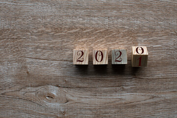 Top view. Wooden cube with word 2020 2021 New Year concept on Wood table background. Closeup and copy space on left for design or text.