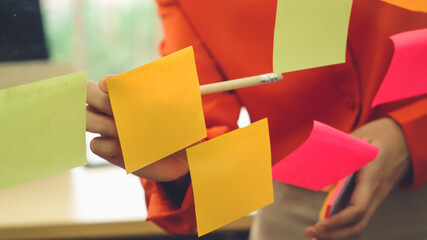 Business people work on project planning board in office and having conversation with coworker...