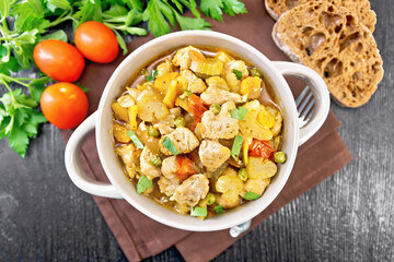Chicken with vegetables and peas in saucepan on board top