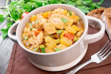 Chicken with vegetables and peas in saucepan on board