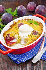 Crumble with plum and ice cream in brazier on wooden board