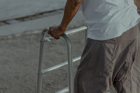 Close up image of old Asian man with walking frame in park.