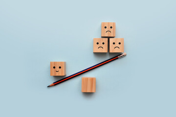 Wooden cubes in the form of scales with drawings of sad and cheerful faces. The choice of positive...