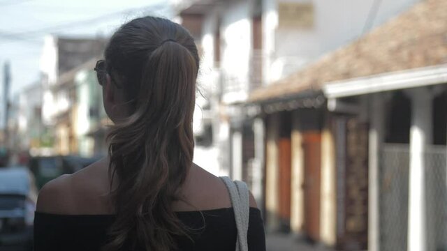 local lady looks for shop walking along center against blurry buildings and transport backside view slow motion. Concept leisure city environment