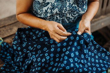 Asian woman's hand is embroidered with tribal native fabric (dyed indigo color). folk art, crafts.
