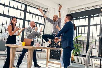 Excited diverse business team employees screaming celebrating good news business win corporate success, happy multi-ethnic colleagues workers group feeling motivated ecstatic about great achievement