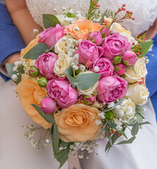 Bride and groom hold wedding bouquet close-up