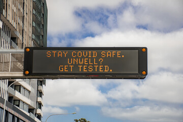 Changeable electronic dynamic road sign reads: -Stay COVID safe. Unwell. Get tested- on the city...