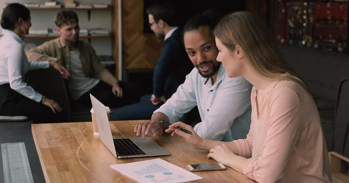 Young multi racial professionals african and caucasian corporate staff sit at table in co working modern office using laptop make financial report analysis research. Teamwork and cooperation concept