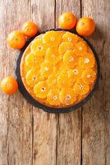 Delicious cut tangerine pie close-up on a slate board on the table. Vertical top view from above