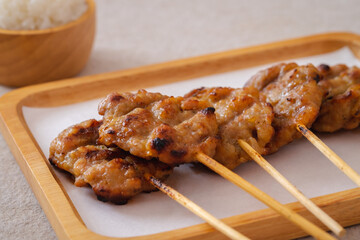 Barbecue pork or grilled pork skewer on plate and sticky rice in bowl, Thai street food