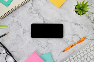 Flat Lay or Top View Smartphone on Marble Office Desk or Office Table Include Stationery as Computer Keyboard,Pen,Stick Note,Office Plants,Spiral Notebook,Ruler,Pencil,Glasses
