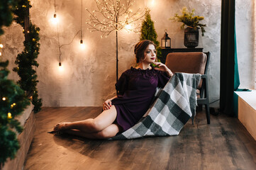 beautiful young girl for christmas in a happy mood against the background of a christmas tree and lights indoors