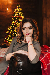 beautiful young girl for christmas in a happy mood against the background of a christmas tree and lights indoors