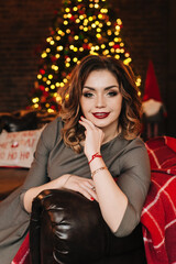 beautiful young girl for christmas in a happy mood against the background of a christmas tree and lights indoors