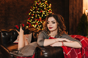 beautiful young girl for christmas in a happy mood against the background of a christmas tree and lights indoors
