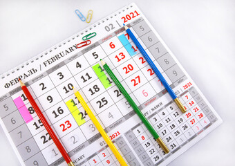 Colored pencils lying on a calendar page for 2021