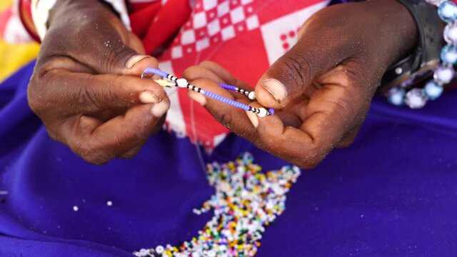 Making of handmade jewellery. Masai african women hands, top view, close up. Island of Zanzibar, Tanzania, East Africa