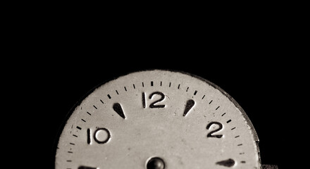 Vintage wall clock on a dark background. Selective focus. Vintage light toning. Grunge style backdrop