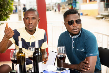 a group of friends sitting around a table speaking bottles.