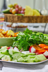 Sliced salad of cucumbers, tomatoes, radishes and herbs on a plate on a served table. Healthy eating.