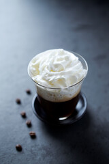 Coffee with whipped cream on dark stone background. Close up. 