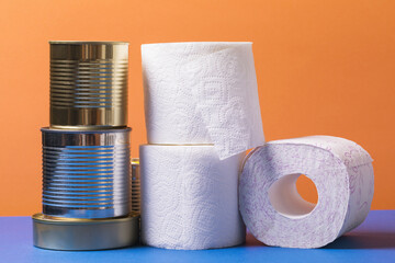 Various cans of canned food and rolls of toilet paper on a colored background. Concept food poisoning