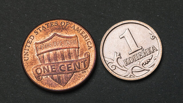 One Russian kopeck and an American cent on a dark background