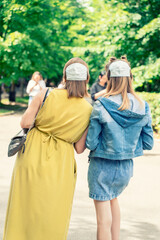 two women put on disposable masks on the back of their heads. not wearing the mask correctly. protest against the mask regime. covid dissidents