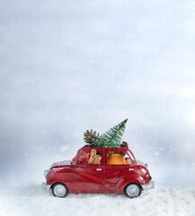 Christmas red car carying christmas tree and decorations. Christmas card concept Vertical imge with copy space