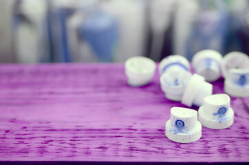 The soiled blue nozzles from the paint sprayer lies on a purple plank on a background of a many...